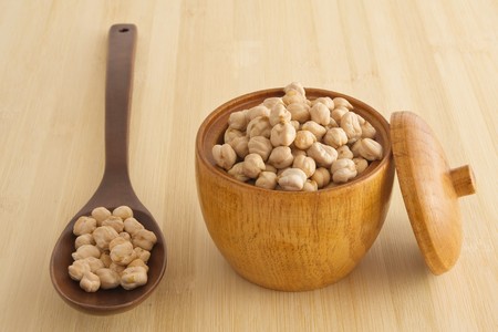 Chickpeas in a bowl and on a wooden spoonの写真素材