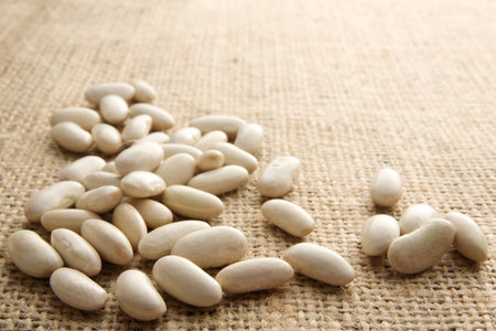 White beans scattered on burlap with copy space
