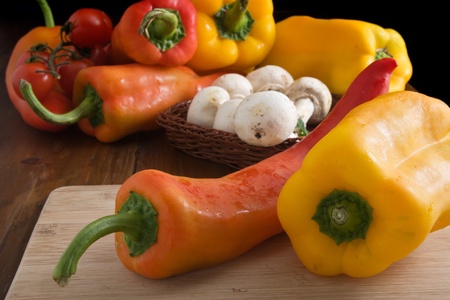 Colorful fresh peppers on a wooden cutting boardの写真素材