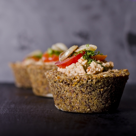 vegan raw food quiche with nut filling and vegetables on topの写真素材