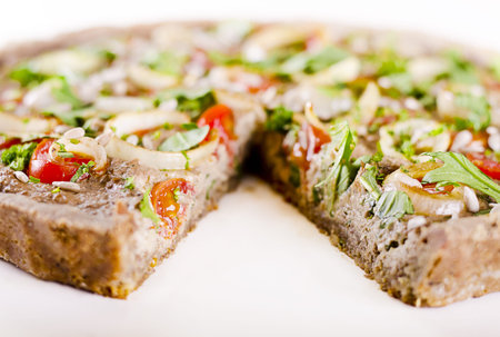 vegan raw food quiche with nut filling and vegetables on topの写真素材
