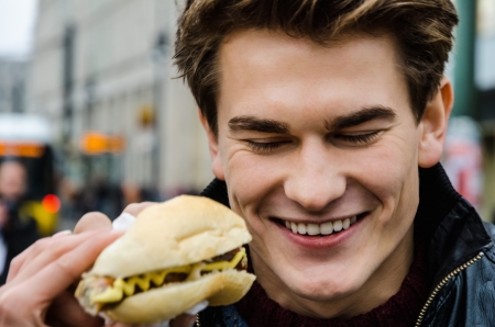 Closeup of happy young man with hotdogの写真素材