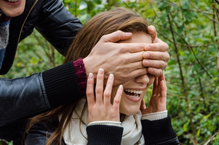 Cropped image of man's hands covering woman's eyes in parkの写真素材