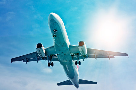 departing plane in the sun seen from below