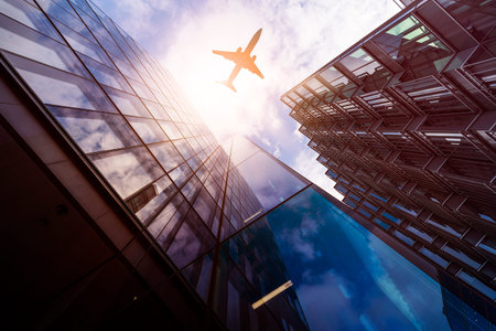 plane flying over highrise office buildings in the sun, financial district London, Great Britain