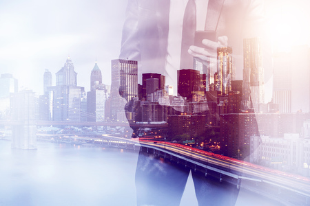 double exposure image of a business man using a smartphone device during sunset overlay with cityscape image. modern life and business conceptの写真素材