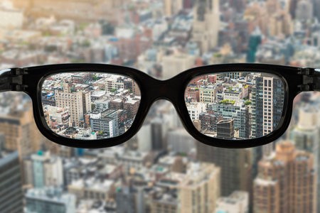 cityscape view focused in glasses lenses, vision concept