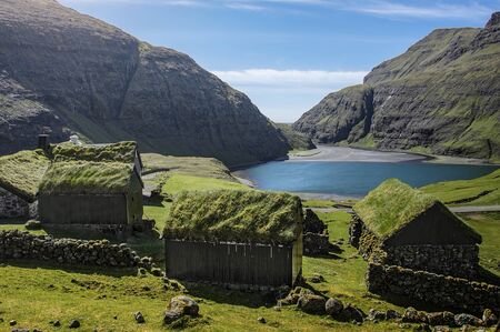 mountain village Saksun with grass roofed houses on the Faroe Islands on a sunny dayの写真素材