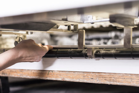 printing operator working on an offset printing maschine checking the final print