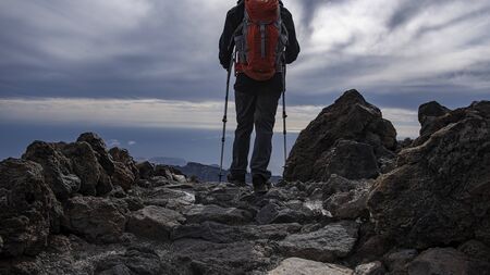 full equipped hiker walking on a rocky mountain pathの写真素材