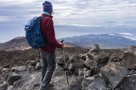 full equipped senior hiker standing on a rocky mountain top with scenic viewの写真素材