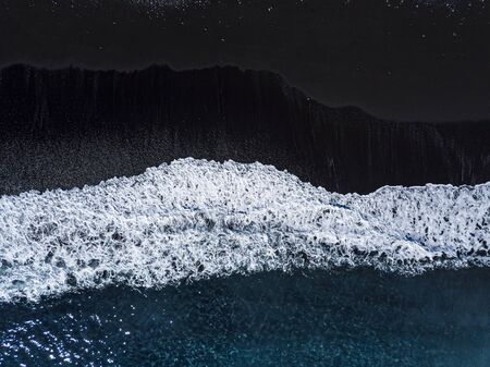 Aerial view of a black beach with volcanic sand seen from aboveの写真素材