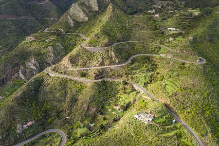Aerial view of a winding road along a large mountainの写真素材