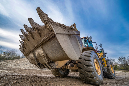 Yellow loader with a large bucket on the construction of the road.