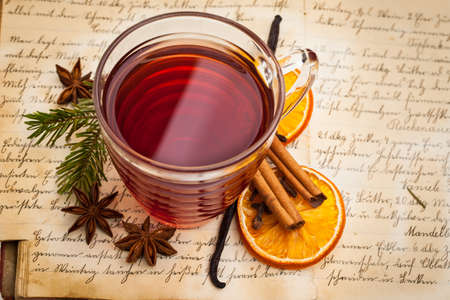 Hot spiced wine with spices on an old cookbook from aboveの写真素材