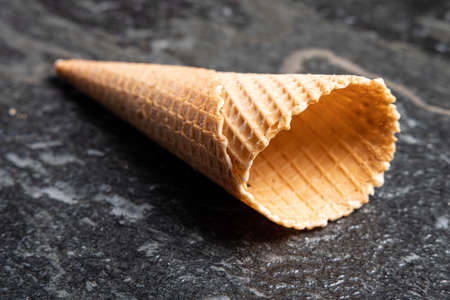 food and drink - icecream: Empty crispy ice cream waffle cone on black lying on a black stone or tableの写真素材