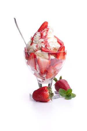 A strawberry sundae with whipped cream and a spoonの写真素材