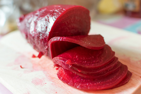 Slicing of boiled beet for salad on wooden cutting board closeup tastyの写真素材
