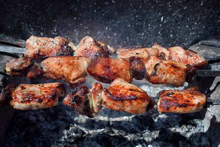 Pieces of grilled pork with red crust on brazier over the coals cookingの写真素材