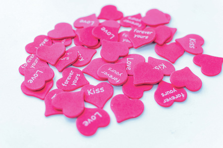 Pile of pink hearts as symbol of love on white background with text on pieces happyの写真素材
