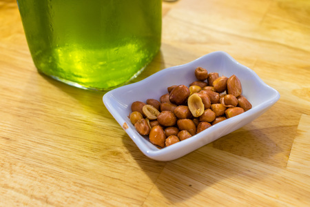 Salted fried peanuts in plate near green beer on a tableの写真素材