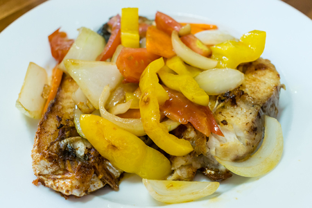 Fried crunchy fish saba with yellow pepper and onion on white plate in cafeの写真素材