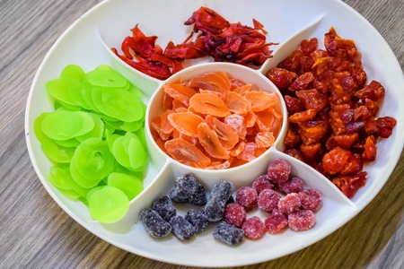 Sweet colorful dried apricot, tomatoes, hibiscus on white plateの写真素材