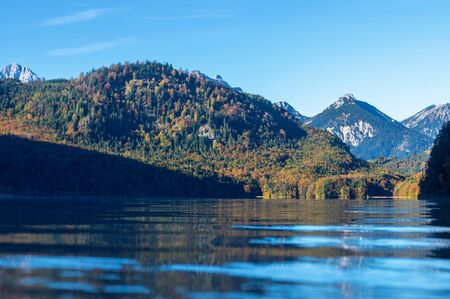 Autumn forest by the lake and snow on top of the Alps in morning sunの写真素材