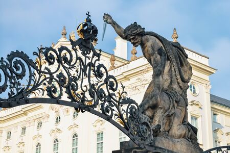 Sculpture of a man with a dagger above the gate against the background of an old building in Pragueの写真素材