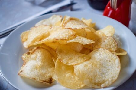 White plate with delicious golden potato chips in cafeの写真素材
