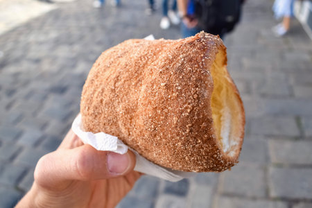 Hand with fresh pastries trdelnik and sugar on the street in Prague