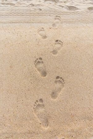 Deep bare footprints with fingers on sand at the beachの写真素材