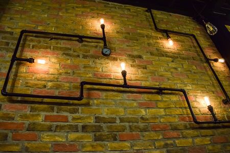 Vintage glowing light bulbs on brick wall as a decorationの写真素材