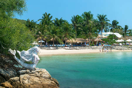 NHA TRANG, VIETNAM - APRIL 19, 2019: Sculpture of a mermaid on beach and thatched houses on sand in the tropicsのeditorial素材