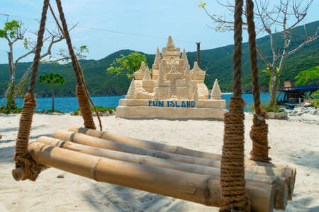 NHA TRANG, VIETNAM - APRIL 19, 2019: Swing made of ropes and bamboo and sand castle on beach in the tropics with clear waterのeditorial素材