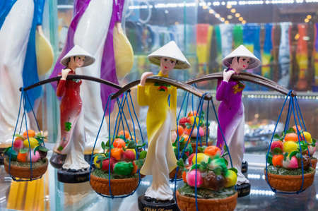 NHA TRANG, VIETNAM - APRIL 19, 2019: Figurine of a girl in a Vietnamese hat and with baskets of fruits in storeのeditorial素材