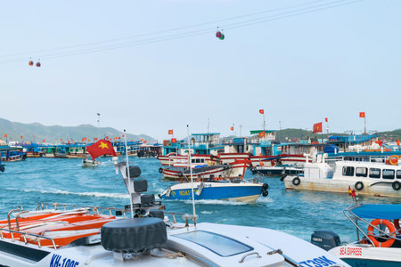 NHA TRANG, VIETNAM - APRIL 19, 2019: Boats with flags of Vietnam in port at sea and funicular