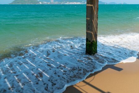Shadow from wooden platform and support with moss on the sandy seashoreの写真素材