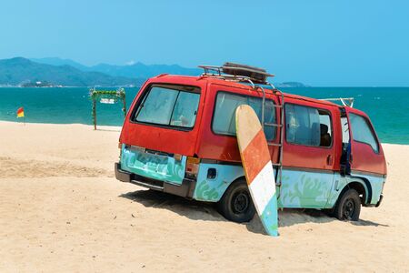 Old bus in the sand and surfboard on the beachの写真素材