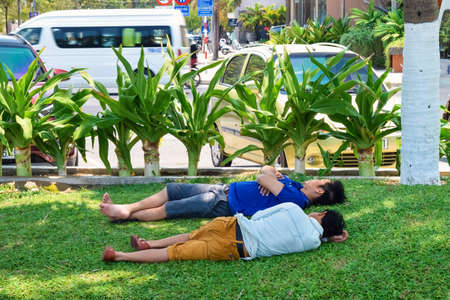 NHA TRANG, VIETNAM - APRIL 21, 2019: Asians are tired of the heat and lie on green lawn in the parkのeditorial素材