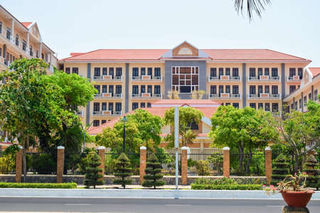 Administration building with a beautiful facade behind fence and tropical treesの写真素材