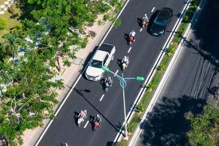 NHA TRANG, VIETNAM - APRIL 21, 2019: Cars and motorcyclists on the road with palm trees along the edges from heightのeditorial素材