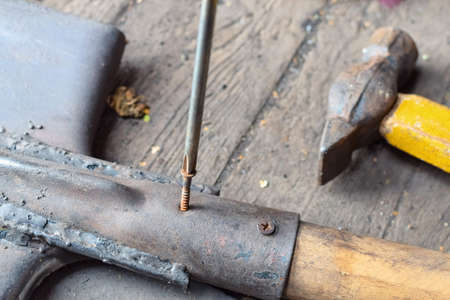 Screwing rusty screw into an old shovel with a screwdriverの写真素材