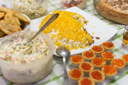 Salad with yellow corn and mayonnaise on plate and profiteroles with red caviarの写真素材