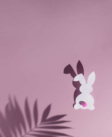 Minimalistic composition layout. Easter bunny on pastel pink background with palm tree shadow.の写真素材