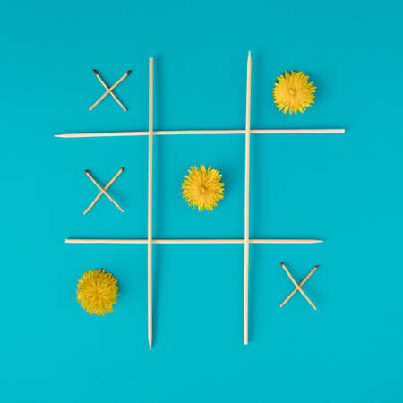 Nature vs Fire. XOX game with dandelions and matches on cyan background.の写真素材