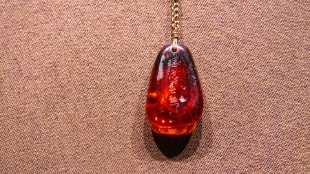Amber pendant on a brown background. Place for text.