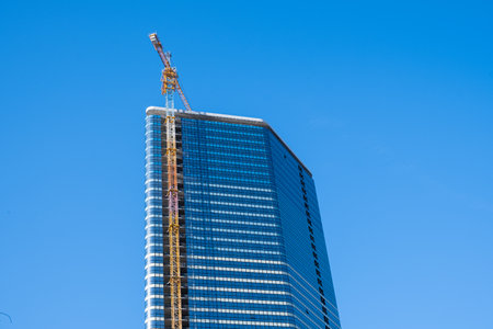 High-rise building under construction with crane on blue sky background.の写真素材