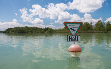 Stop, stop sign for nature protection landscape in german language, taken from a kayak. Water plants, reed and Iceland Wort. Clear, cloudy day. In Woerthsee, Bavaria, Starnberg, Germany.の写真素材