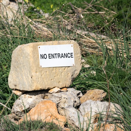 Stone with a white no entrance sign lettering in a green grass fieldの写真素材